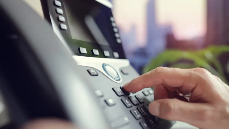 Hand wählt auf der Tastatur eines Festnetztelefons